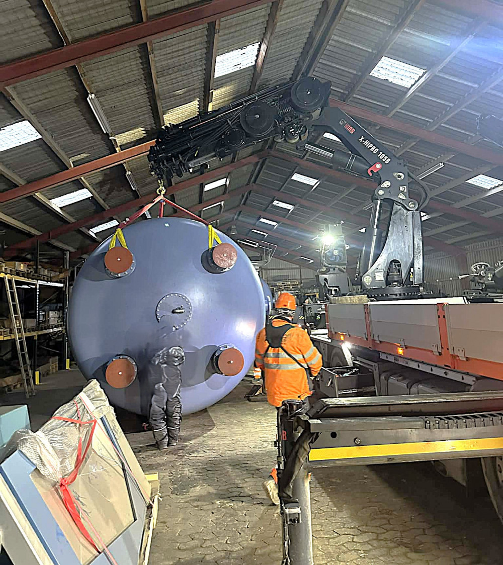 Vandrensningsbeholder løftes inde i en hal. 